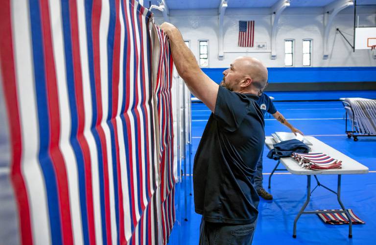 City HVAC technition Sean Burch of the Public Properties staff for Concord puts the front covers on the voting booths for Ward 4 at the Green Street Community Center on Monday, September 9, 2024.