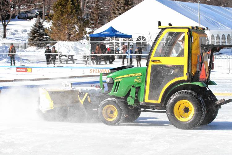 A small John Deere snow plow sweeps the snow off the ice in preparation for upcoming games.