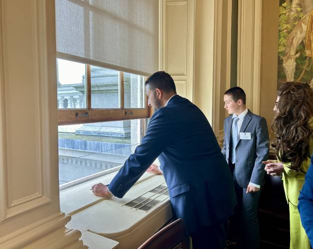 Sen. Daryl Abbas (left), a Republican from Salem, looks out the window of the Senate chamber at protesters who chanted 