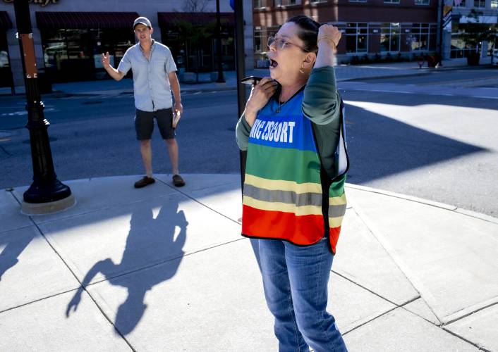 Equality Health Center clinic escort Kari Stephen yells over the voice of Danny Hendrick as he recites scripture on South Main Street in Concord on Friday morning, June 23, 2023. Stephen says the anti-abortion forces that come to the clinic are more aggressive since the Hobbs Supreme Court decision.