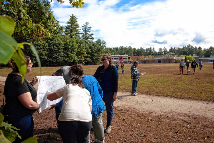 Participants look over maps of the trails behind Millbrook and Broken Ground schools as they visit the site proposed for the new middle school on Saturday, September 28, 2024.