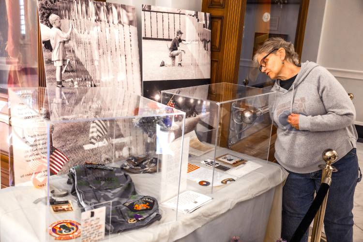 Gail Gordon looks over the Vietnam War 50th Anniversary display that is displayed in the New Hampshire State House Hall of Flags on the day the Vietnam War came to end.