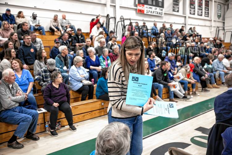 Pembroke fourth grade teacher Lindsay Powles hands out leaflets explaining what the support staff does in the schools and why the teachers support them during the Pembroke School Meeting in the gym at Pembroke Academy on Saturday, March 9, 2024.