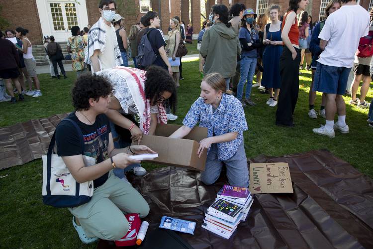 Three Dartmouth students who declined to give their names set up a “Liberation Library” at the end of an “Endowment is Political” rally on Baker Lawn in Hanover. Student organizers plan to hold teach-ins and community-building events in the space, which they will occupy daily. 