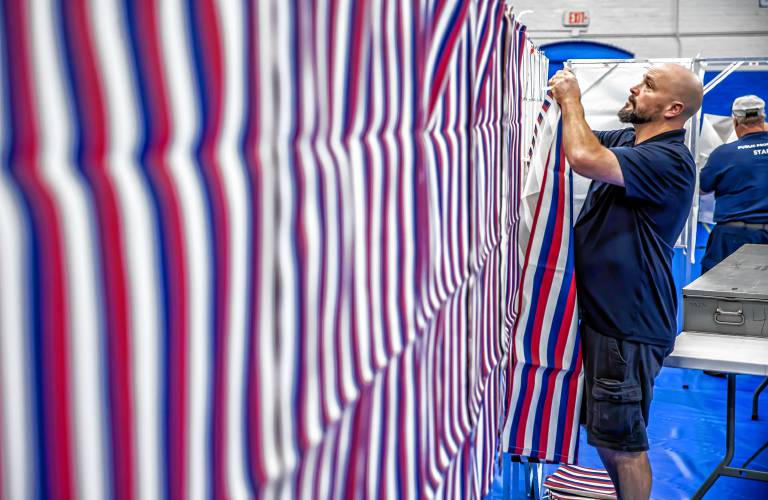 City HVAC technician Sean Burch of the Public Properties staff for Concord puts the front covers on the voting booths for Ward 4 at the Green Street Community Center on Monday, September 9, 2024.
