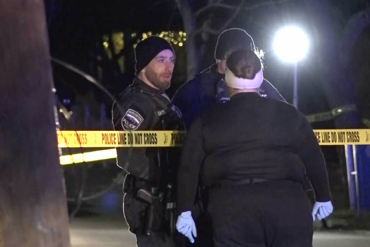 In this still frame from video provided by WCAX-TV law enforcement officers speak near police tape near a scene Saturday, Nov. 25, 2023 where three men of Palestinian descent were shot and injured, in Burlington, Vt. Burlington Police Department arrested Jason J. Eaton, suspected in the shooting of three young men, who were attending a Thanksgiving holiday gathering near the University of Vermont campus Saturday evening. (WCAX-TV via AP)