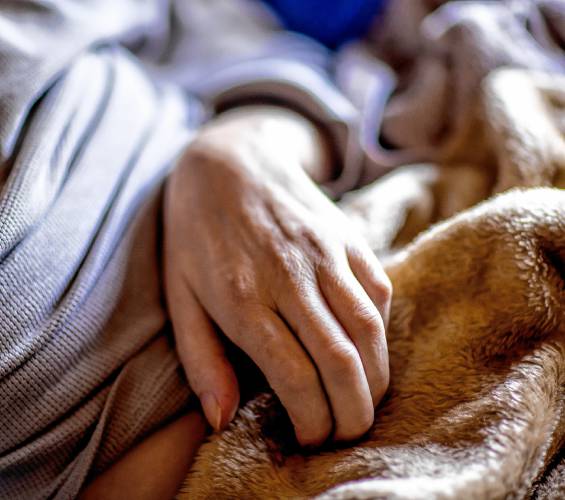 John Jones lies in the hospital bed in the living room of his Franklin house on October 18, 2023 as he tries to move his left arm.