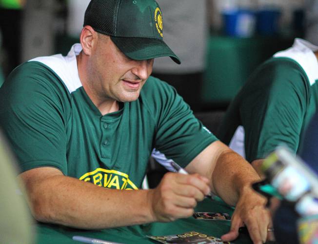 New Hampshire lieutenant Bob Mancini signs a baseball card for a fan ahead of Saturday's North Woods Throwdown softball game against the Maine Game Wardens on Saturday at Gill Stadium in Manchester.