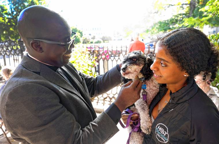 Rev. Jean Beniste blesses the family dog, Charlie, as his daughter, Annelise, holds him on Saturday.