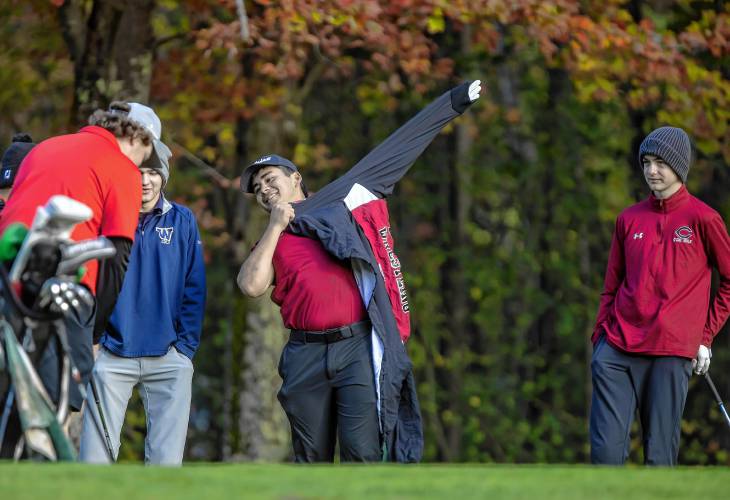 Concord’s Carl Sirrianna puts on a coat at the first hole at Canterbury Woods Country Club on Tuesday. The temperature was in the 40s as the teams teed off for the NHIAA Division I team golf championship.