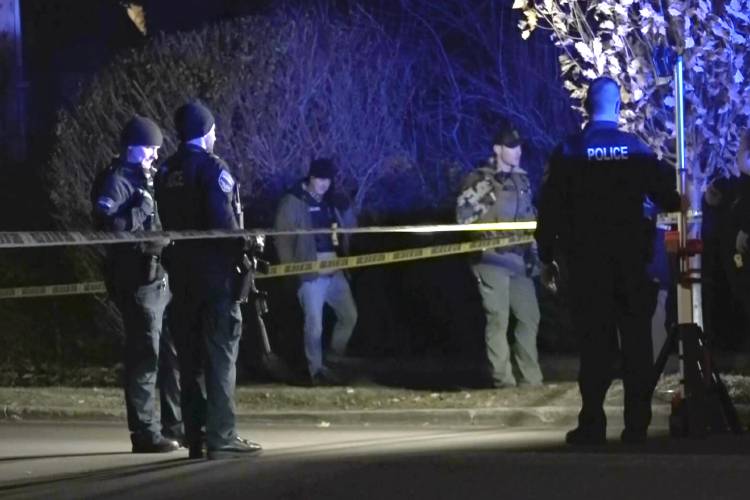 In this still frame from video provided by WCAX-TV law enforcement officers stand by police tape near a scene Saturday, Nov. 25, 2023 where three men of Palestinian descent were shot and injured, in Burlington, Vt. Burlington Police Department arrested Jason J. Eaton, suspected in the shooting of three young men, who were attending a Thanksgiving holiday gathering near the University of Vermont campus Saturday evening. (WCAX-TV via AP)