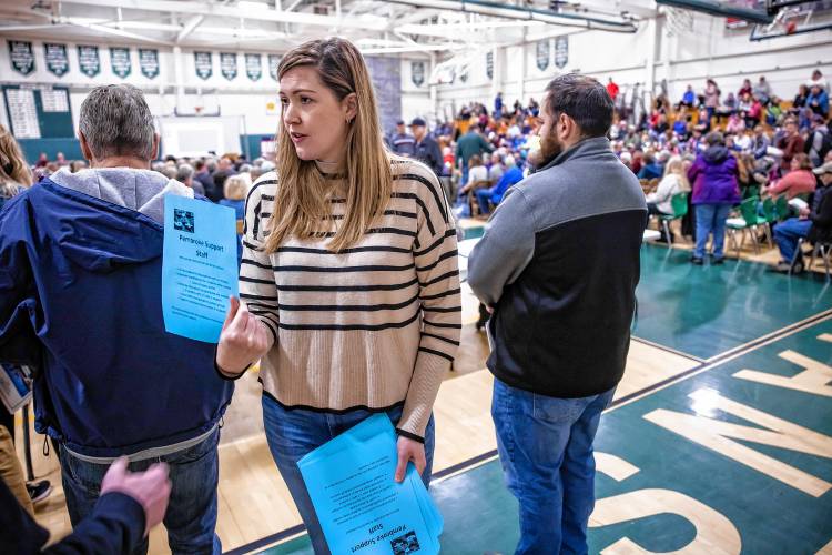 Pembroke fourth grade teacher Lindsay Powles hands out leaflets explaining what the support staff does in the schools and why the teachers support them during the Pembroke School Meeting in the gym at Pembroke Academy on Saturday, March 9, 2024.