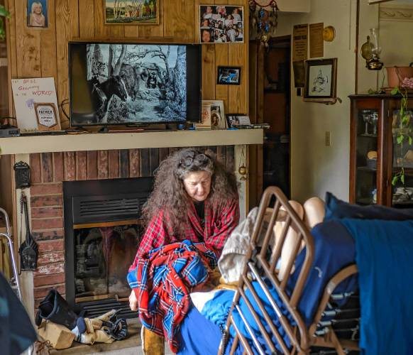John Jones lies in the hospital bed in the living room of his Franklin house as his partner,  Jessica Helfenstein adjust his bed while he watches Gunsmoke on August 10, 2023. 