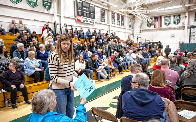 Pembroke fourth grade teacher Lindsay Powles hands out leaflets explaining what the support staff does in the schools and why the teachers support them during the Pembroke School Meeting in the gym at Pembroke Academy on Saturday, March 9, 2024.