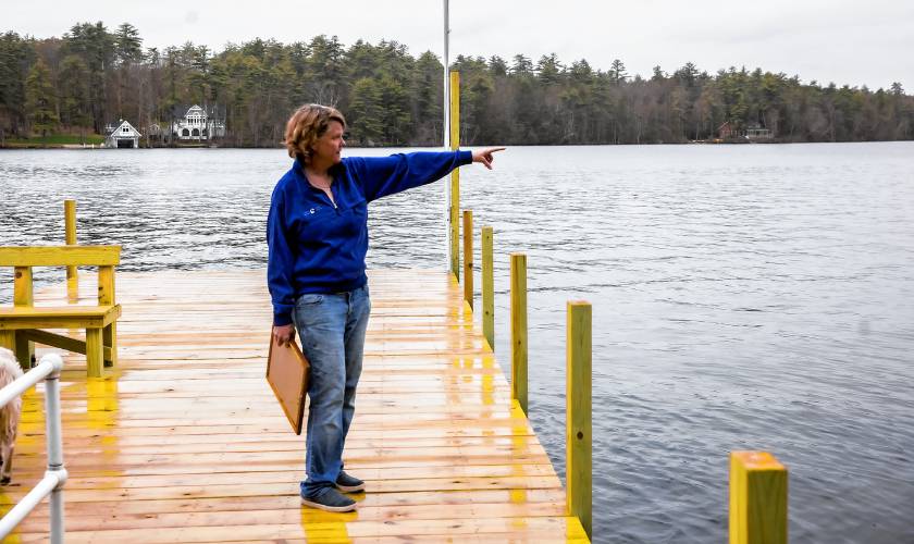 Laura Prichard points where the boat approached the new dock on the shore of the Keewaydin area of Lake Winnipasaukee. The former lake community dock was destroyed in a boat accident last year.