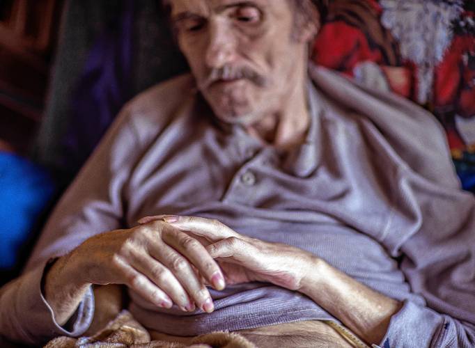 John Jones lies in the hospital bed in the living room of his Franklin house on October 18, 2023 as he tries to move his left arm.