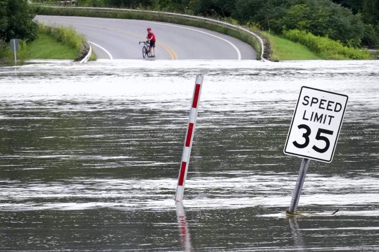A cyclist pauses to look at the Winooski River, which overflowed its banks covering nearly a quarter mile of roadway, after remnants of Hurricane Beryl caused flooding, Thursday, July 11, 2024, in North Williston, Vt. (AP Photo/Charles Krupa)