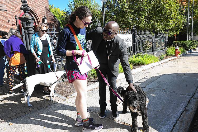 Rev. Jean Beniste, rector of St. Paul’s Church, blesses Kelly Cleland’s dog, Nelly, on Saturday in front of the church on Park Street. Cleland said that Nelly is her best friend: “There’s so much joy here and I like to be around joy, and it’s good for her as well.”
