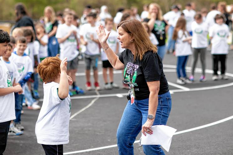 Allenstown Community School Principal Shannon Kruger gives a high five to second grader Mason Pieberl as students and faculty gather for a drone photo outside the school on the first day of classes at the new facility. 