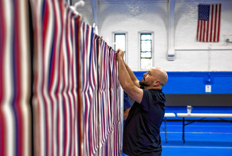 City HVAC technician Sean Burch of the Public Properties staff for Concord puts the front covers on the voting booths for Ward 4 at the Green Street Community Center on Monday, September 9, 2024.