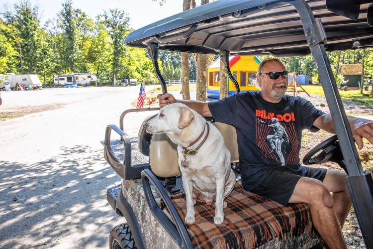 New Hampshire resident Daniel Couture and his dog, Tucker, use a golf cart to get around the campground.