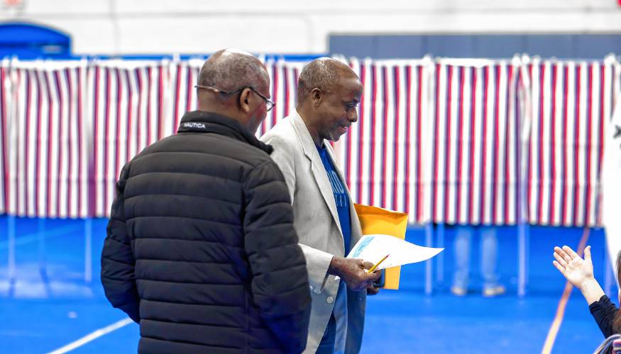 Kayitani Ndutiye (right) is directed to the voting booths at the Green Street Community Center in Concord to vote for the first time in the New Hampshire Primary on January 23, 2024.