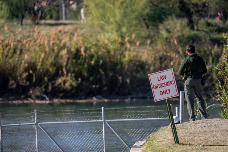 An officer stands guard on the banks of the Rio Grande river at Shelby Park on Jan. 12, 2024, in Eagle Pass, Texas.