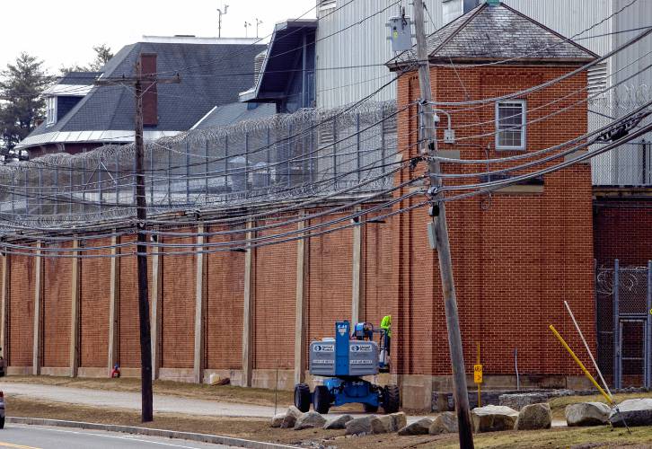 A worker uses a lift to work on the outside brick wall of the New Hampshire State Prison on North State Street on Wednesday, March 20, 2024.