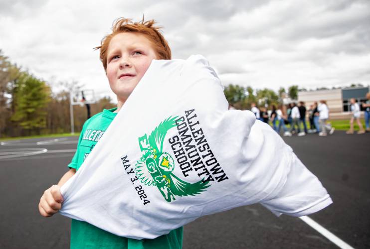 Allenstown Community School second grader Mason Pieberl puts on the tee shirt kids got as students and faculty gather for a drone photo outside the school on the first day of classes at the new facility.  Faculty wore black tee shirts commorating the first day of school and the students wore white tee shirts given by a school employee.