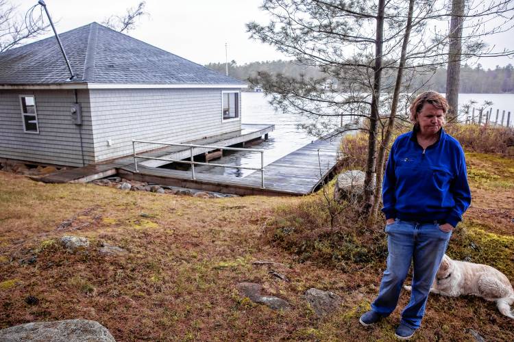 Laura Prichard near the boathouse on the shore of the Keewaydin area of Lake Winnipasaukee. The former lake community dock was destroyed in a boat accident last year.