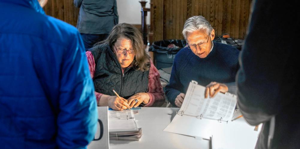 Warner supervisors of the checklist Mary Pelkey and Michael Brown check in residents at the Warner Town Meeting on March 12.