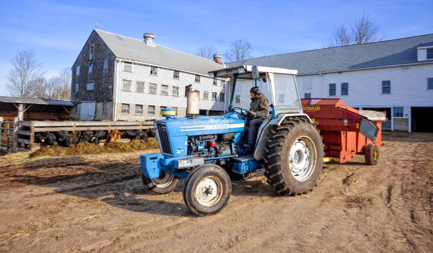 Jeff Moore of Windswept Maples Farm in Loudon passes by the open air feeding trough for his cows on Saturday. Moore was planning on building a south facing pitched roof over the open air trough for solar collection and protection from the elements for his herd.