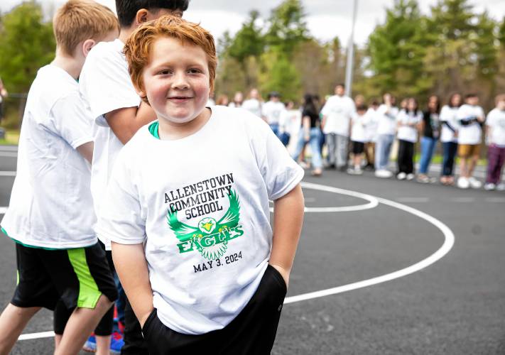 Allenstown Community School second grader Mason Pieberl shows the tee shirts kids got as students and faculty gather for a drone photo outside the school on the first day of classes at the new facility.  Faculty wore black tee shirts commorating the first day of school and the students wore white tee shirts given by a school employee.