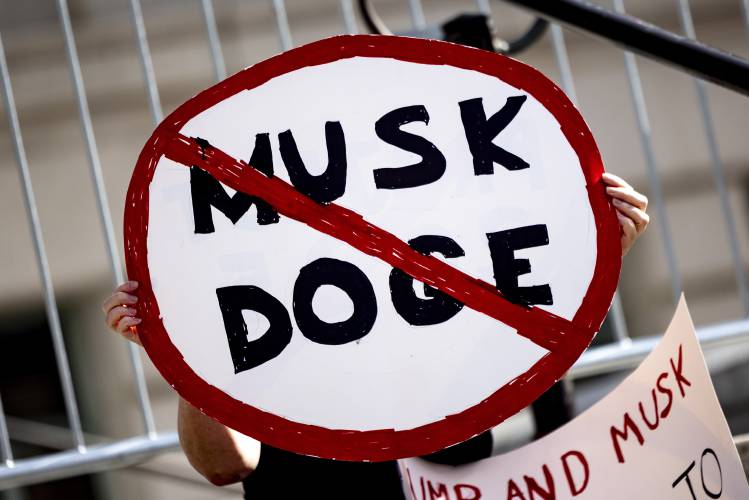 A demonstrator holds a sign during a rally to protest President Donald Trump and Elon Musk policies Feb. 17, 2025, in Los Angeles. (AP Photo/Etienne Laurent, File) A demonstrator holds a sign during a rally to protest President Donald Trump and Elon Musk policies Feb. 17, 2025, in Los Angeles. (AP Photo/Etienne Laurent, File)