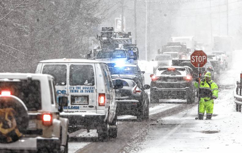 ABOVE: Flagger Dianna St. Laurent directs traffic for a communications company that was working on lines on Route 3 in Tilton during the snowstorm on Tuesday. St. Laurent traveled from Pittsfield in the snow for the work.