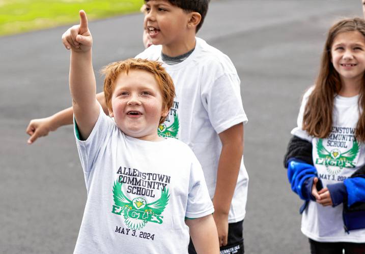 Allenstown Community School second grader Mason Pieberl looks up at the drone as students and faculty gather for a drone photo outside the school on the first day of classes at the new facility.  Faculty wore black tee shirts commorating the first day of school and the students wore white tee shirts given by a school employee.