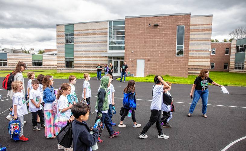 Allenstown Community School Principal Shannon Kruger (right) directs as students and faculty gather for a drone photo outside the school on the first day of classes at the new facility.  Faculty wore black tee shirts commorating the first day of school and the students wore white tee shirts given by a school employee.