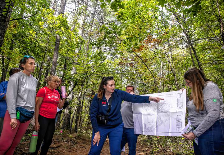 Norbis project engineer Morgan Dunson (center) shows maps as the group of school officials and members of the public walks the area behind Mill Brook and Broken Ground schools on the site tour for the proposed middle school on Saturday, Sept. 28.