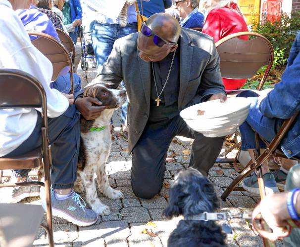 Rev. Jean Beniste, rector of St. Paul’s Church, blesses a dog on Saturday, October 5, 2024, in front of the church on Park Street.