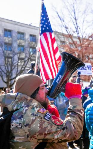 Alex Finn of Merrimack uses a megaphone to chant at the hundreds of people that rallied in front of the State House on Wednesday, February 5, 2025 as part of the national movement to protest the Project 2025.