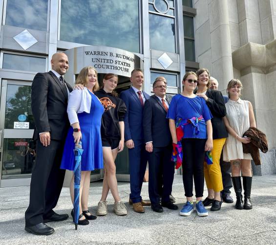 FILE - Two teens challenging New Hampshire's new law banning transgender girls from girls' sports teams, Parker Tirrell, third from left, and Iris Turmelle, sixth from left, pose with their families and attorneys in Concord, N.H., Aug. 19, 2024. (AP Photo/Holly Ramer, File)
