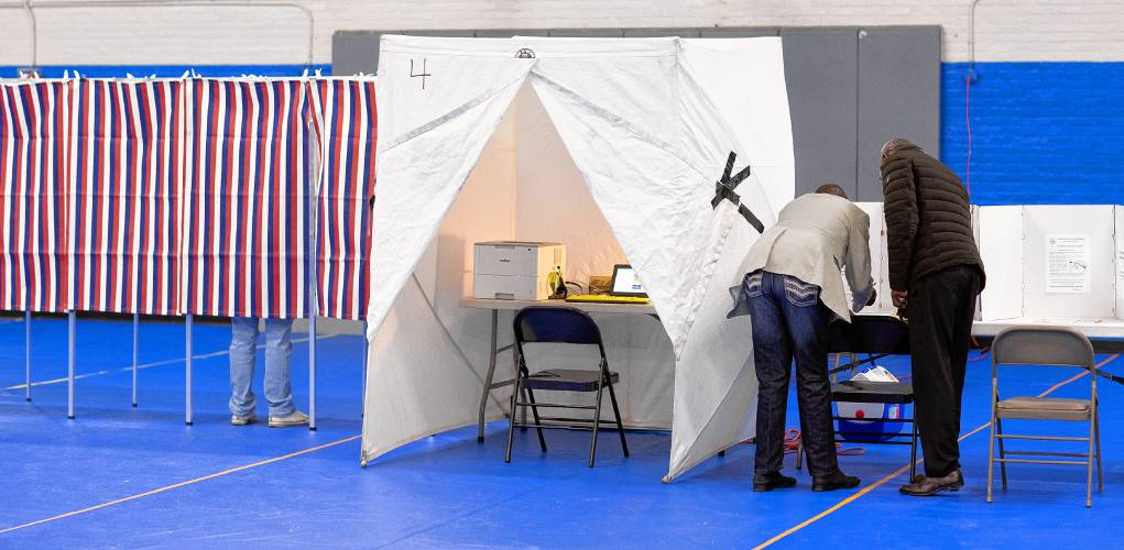 Clement Kigugu (right), the director at Overcomers, who had given him a ride to the location, helps Kayitani Ndutiye with translations as Ndutiye votes for the first time in the United States at the Green Street Community Center on Primary Day in New Hampshire.