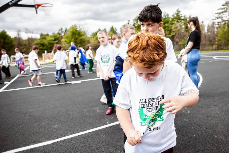 Allenstown Community School second grader Mason Pieberl shows the tee shirts kids got as students and faculty gather for a drone photo outside the school on the first day of classes at the new facility.  Faculty wore black tee shirts commorating the first day of school and the students wore white tee shirts given by a school employee.