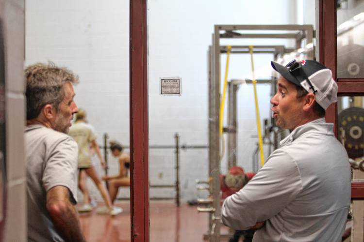 Chris Beyer, left, the Concord High girls’ cross country head coach, updates Athletic Director Stephen Largy on the team before their next event outside of the weight room.
