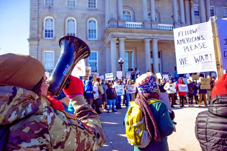 Alex Finn of Merrimack uses a megaphone to chant at the hundreds of people that rallied in front of the State House on Wednesday, February 5, 2025 as part of the national movement to protest the Project 2025.