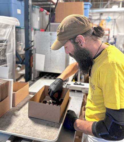 Chocolatiers at the Granite State Candy Shoppe factory on Hall St. Concord prepared chocolates for Valentine's Day on Monday, Feb. 3. Justin Abbott removed chocolate-covered coconut candies from a conveyor belt and put them into a box.