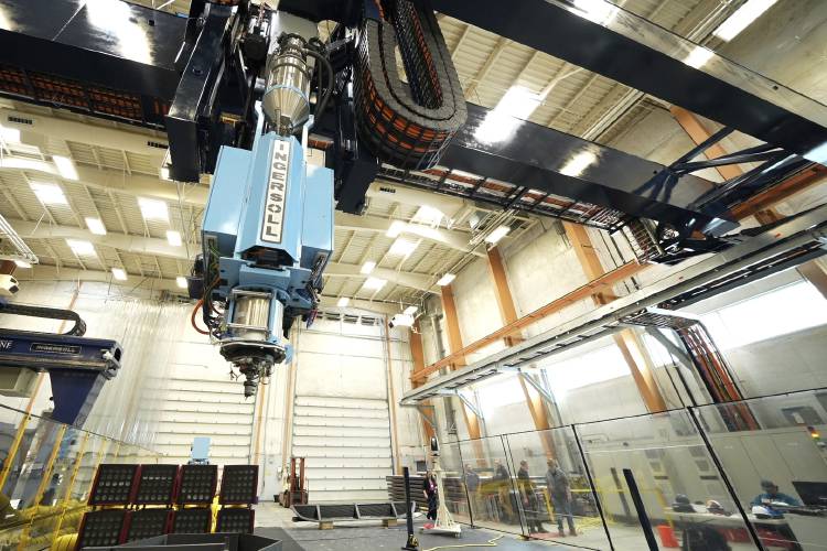 The world's largest 3D printer is seen Tuesday at the University of Maine, in Orono, Maine. To the right are exterior and interior images of a previous 3D-built home.