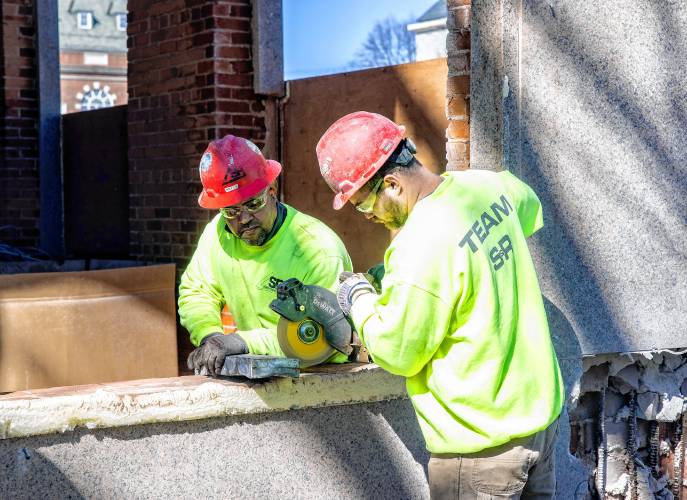 A member of the S&R Demolition team out of Lowell, Massachusetts use a circular saw to open the time capsule at the cornerstone of the former DOJ and Mechanics Bank building on North State Street on Tuesday, April 9, 2024.