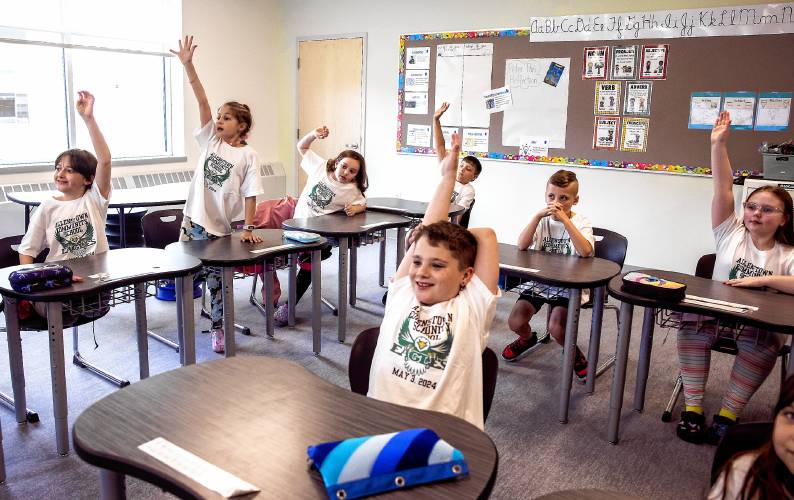 ABOVE: Allenstown Community School third grader Riley Curry (center) is among those raising a hand to answer a math question in teacher Kim Foss’s class on the first day of school at the new facility.