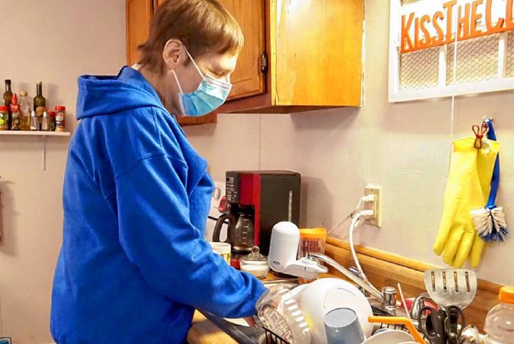 Care provided through the Choices for Independence program can include assistance with bathing, housekeeping, and cooking. Here, caregiver Joan Ilves cleans dishes in Charlestown. (Annmarie Timmins | New Hampshire Bulletin)